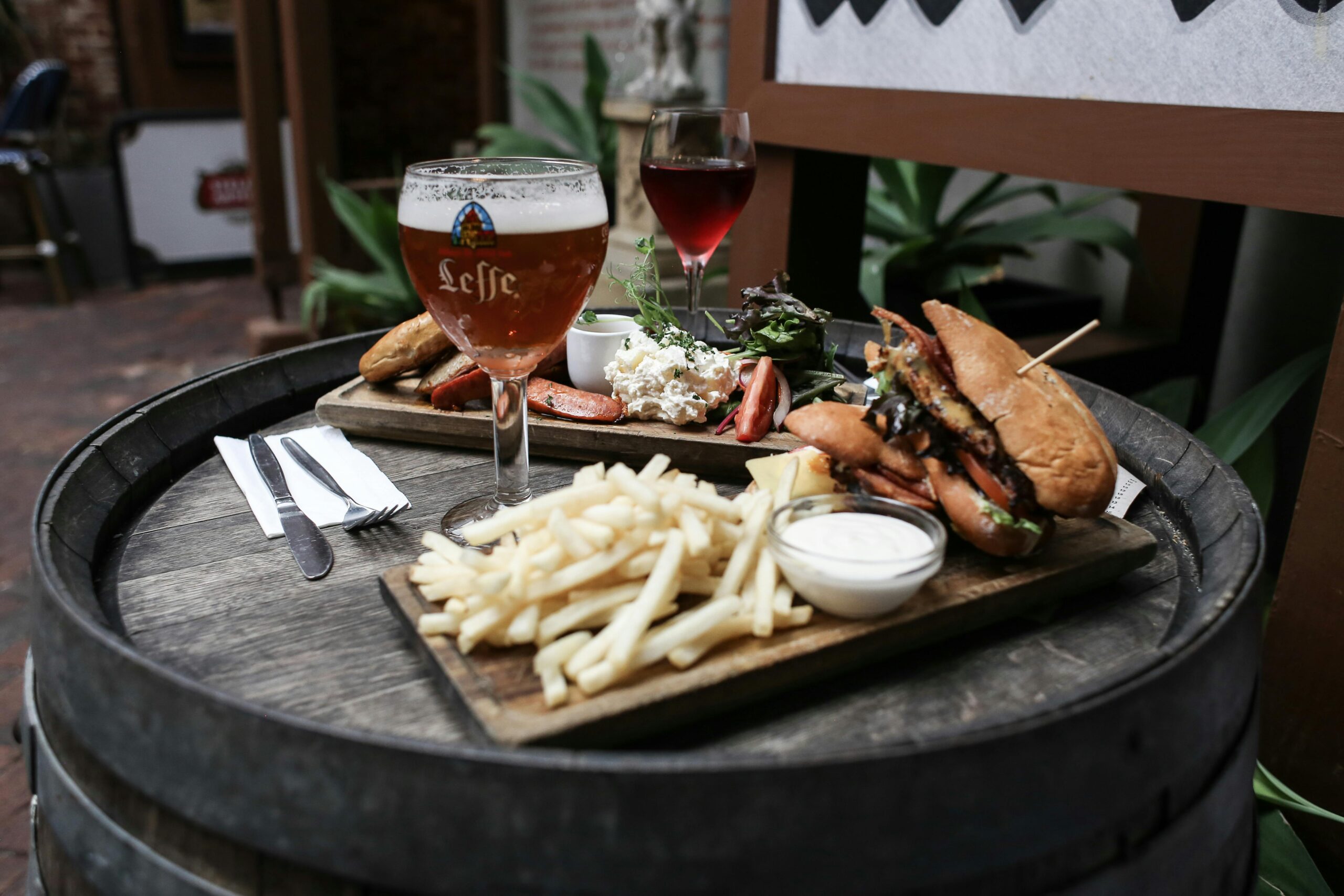 Close-up of a gourmet meal with beer and wine, served on a rustic barrel table. Perfect for food lovers.